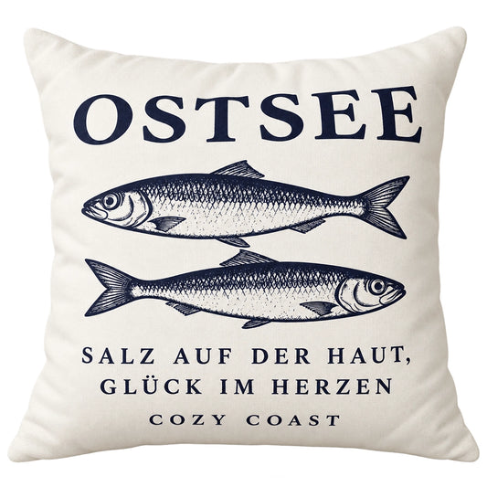 Naturfarbene Cozy Coast Kissenhülle OSTSEE 50 x 50 cm mit dunkelblauen Fischen und dem Spruch „Salz auf der Haut, Glück im Herzen“
